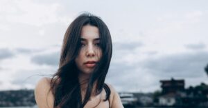 Captivating portrait of a young woman by the waterfront in Türkiye, set against a moody sky.